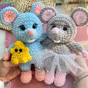 May include: Two plush crochet mouse toys with soft yarn texture. The blue mouse holds a yellow star, while the gray mouse wears a white tulle skirt with silver glitter. Both have pink inner ears, pink noses, and black safety eyes.