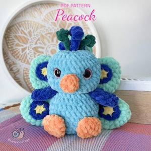 May include: A crocheted peacock plush toy with blue, green and orange accents. The toy has a light blue body, a green and blue crest, and a bright orange beak. The peacock's tail feathers are a mix of green and blue with yellow stars.