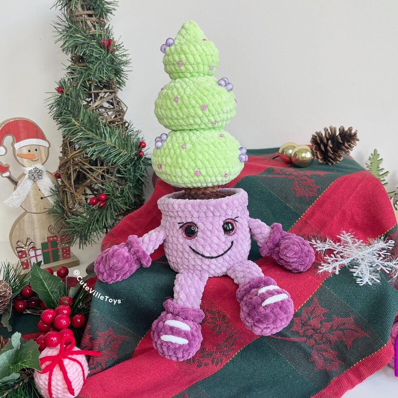 Christmas tree in smiling pot made in different colors: light purple pot with purple mittens and boots. The tree is decorated with colorful beads.