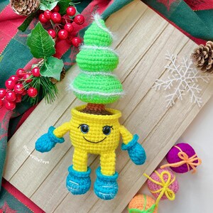 Christmas tree in smiling pot made in different yarn and colors: yellow pot with blue mittens and boots.