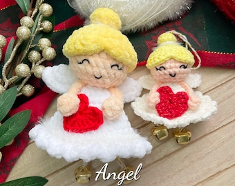 Op de afbeelding: Twee gehaakte engel-versieringen met witte jurken, geel haar en rode harten. De grotere engel houdt een hart in zijn handen. De kleinere engel heeft een hart op zijn borst. De tekst "Angel PDF Pattern" staat onder de versieringen.