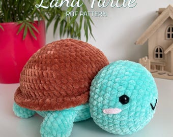 May include: A crocheted land turtle plush toy with a brown shell and a turquoise body. The toy has a cute face with black eyes and a pink blush.