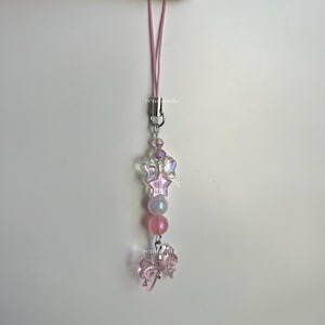 May include: A pink phone charm with a clear iridescent star and butterfly charm, pink beads, and a silver clasp.