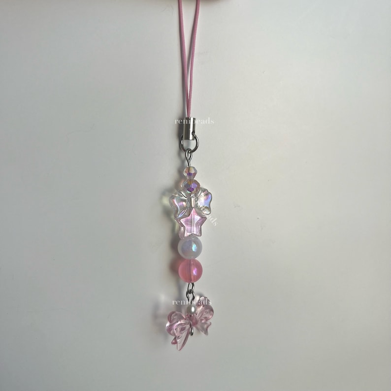 May include: A pink phone charm with a clear iridescent star and butterfly charm, pink beads, and a silver clasp.