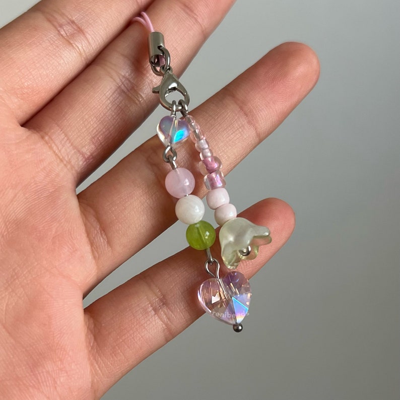 Peut inclure: Un charme en perles rose, vert et blanc avec un charme en forme de fleur et un charme en forme de c&oelig;ur. Le charme est attach&eacute; &agrave; une cha&icirc;ne argent&eacute;e.