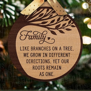 Peut inclure: Ornement de Noël en bois avec un motif d'arbre et le mot "Famille". L'ornement a un centre brun clair avec une bordure marron foncé et un ruban doré. Le texte sur l'ornement se lit comme suit : "Comme les branches d'un arbre, nous grandissons dans des directions différentes, mais nos racines restent unies."