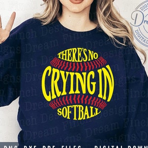 May include: A navy blue sweatshirt with the text "There's no crying in softball" printed on it in yellow and red. The text is inside a red and white softball graphic.
