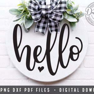 May include: A white round wooden sign with the word "hello" written in black cursive script. The sign is decorated with a black and white checked bow and a sprig of greenery.