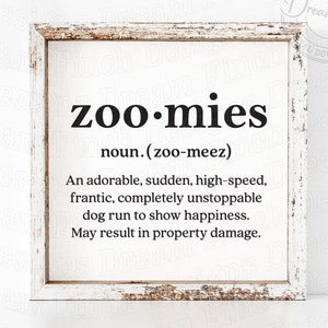 May include: A white wood framed sign with the word "zoo-mies" in black text. The definition of the word is "An adorable, sudden, high-speed, frantic, completely unstoppable dog run to show happiness. May result in property damage."