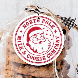 May include: A clear cellophane bag filled with several oatmeal cookies. The bag is tied with twine and a black and white checkered ribbon. A round tag with the words "North Pole Milk & Cookie Company" and a Santa Claus graphic is attached.