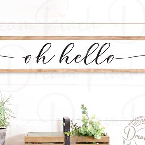 May include: A wooden sign with the text "oh hello" in a cursive font. The sign is on a white wood background.