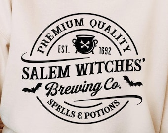 Può includere: Una felpa bianca con un design grafico nero che dice "Premium Quality Est. 1692 Salem Witches' Brewing Co. Spells & Potions".