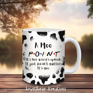 Peut inclure: Une tasse en céramique blanche avec un motif imprimé de vache noir et blanc. La tasse a une poignée noire et dit "A Moo POINT It's like a cow's opinion. It just doesn't matter It's moo."
