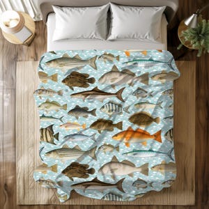 May include: A light blue blanket featuring a pattern of various fish illustrations in shades of brown, orange, and gray. The fish are arranged on a background of white cloud-like shapes. The blanket is on a bed with white pillows.