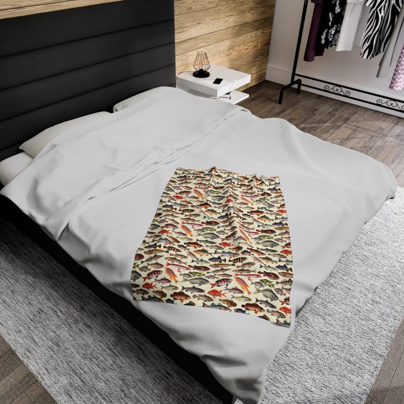 May include: A white throw blanket with a pattern of colorful fish on a cream background.