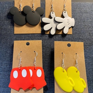 Peut inclure: Quatre paires de boucles d'oreilles pendantes avec diff&eacute;rents motifs de personnages Disney. La premi&egrave;re paire pr&eacute;sente des oreilles de Mickey Mouse noires, la deuxi&egrave;me paire pr&eacute;sente des gants de Mickey Mouse blancs, la troisi&egrave;me paire pr&eacute;sente des shorts de Mickey Mouse rouges avec des pois blancs et la quatri&egrave;me paire pr&eacute;sente des chaussures de Mickey Mouse jaunes.
