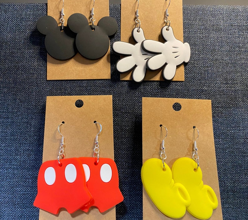 Peut inclure: Quatre paires de boucles d'oreilles pendantes avec diff&eacute;rents motifs de personnages Disney. La premi&egrave;re paire pr&eacute;sente des oreilles de Mickey Mouse noires, la deuxi&egrave;me paire pr&eacute;sente des gants de Mickey Mouse blancs, la troisi&egrave;me paire pr&eacute;sente des shorts de Mickey Mouse rouges avec des pois blancs et la quatri&egrave;me paire pr&eacute;sente des chaussures de Mickey Mouse jaunes.