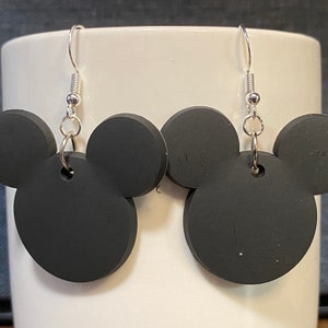 Peut inclure: Une paire de boucles d'oreilles noires en forme de t&ecirc;te de Mickey avec des crochets argent&eacute;s.
