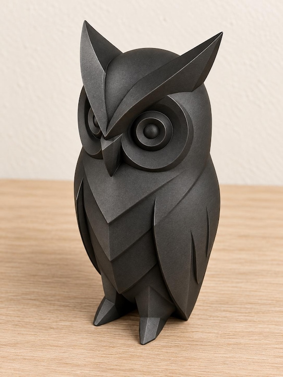 Charcoal owl sculpture, close-up alternate camera angle on pale oak against an ivory wall.