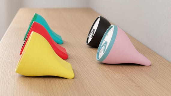Alternate close-up of Fincrest Desk Clock examples on light oak, showing their colored faces, hands and body profiles.