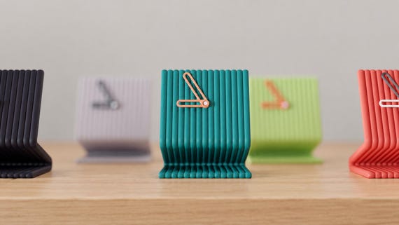 Angled close-up of Linefold Tall Desk Clock examples in contrasting colors on light oak against a gray wall.