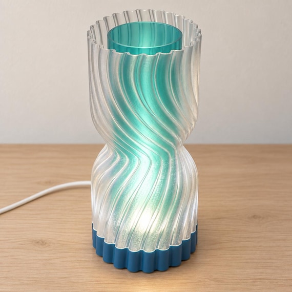 Elevated view of the Lagoon Mist Rillora lamp showing its clear scalloped outer rim, Teal cylindrical inner diffuser, Marine Blue base and white cord.