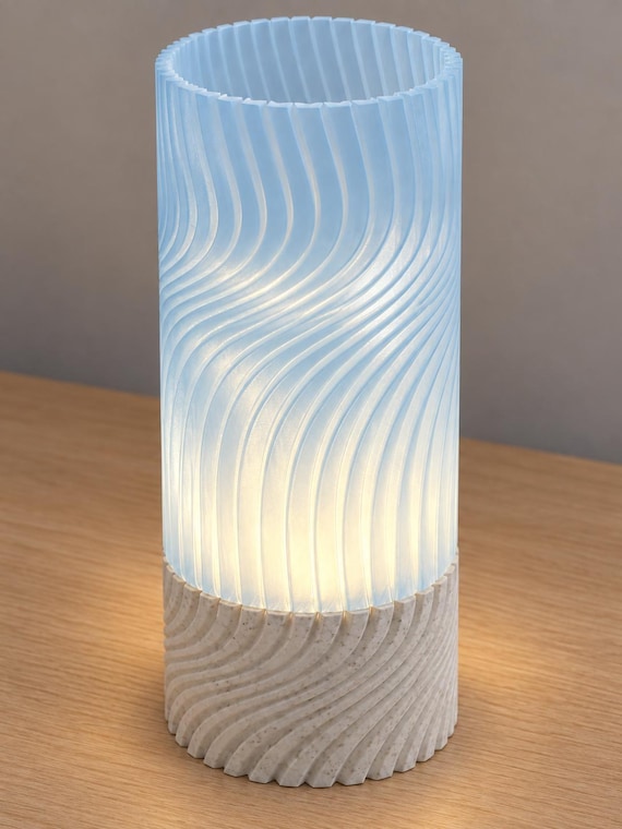 Elevated view of Marble Mist Seravelle with a White Marble speckled base, Ice Blue translucent shade and open ribbed rim, illuminated by a battery tea light without a cord.