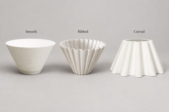 Three ivory white lampshades side by side on a plain warm gray surface, labeled Smooth, Ribbed and Curved, showing their shapes and texture.