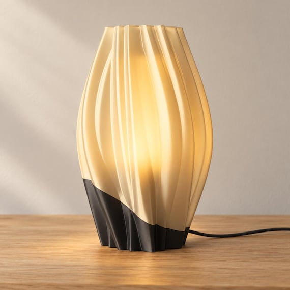 Midnight Amber Orelune lamp with a Charcoal base and softly glowing Mellow Yellow diffuser and flowing outer shade, USB cord visible on an oak tabletop.
