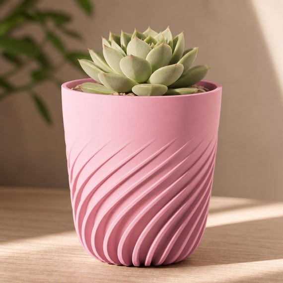 Close-up of a small Flowspire spiral rib planter in Sakura Pink with a succulent