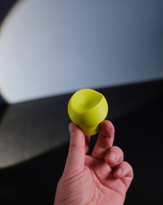 Yellow sculpted cabinet knob held in a hand, showing the recessed center and rounded edge.
