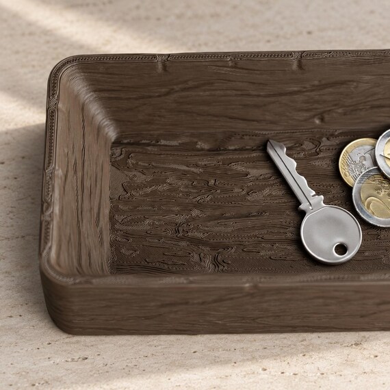 Close-up of the espresso brown Timberfold tray corner and textured basin with a key and coins on a light tabletop