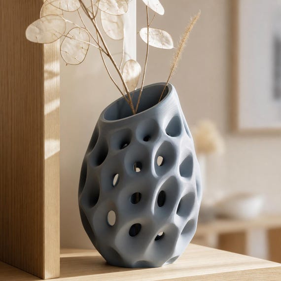 Close-up of the Lacuna Bloom sculptural vase in Blue Grey with pale lunaria stems