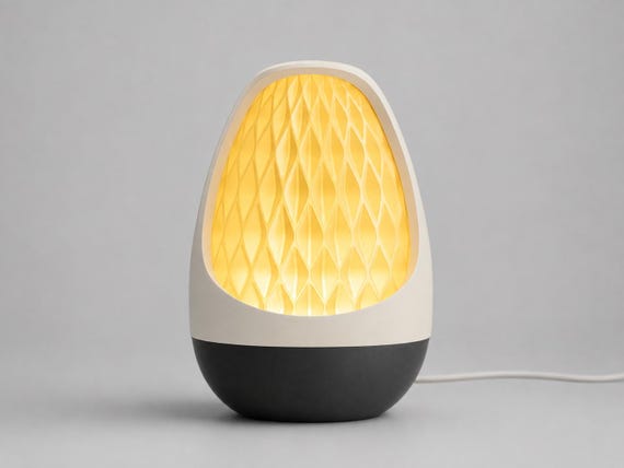 Lumenvale USB lamp in Honeyglow, assembled with a Bone White frame, Charcoal base and glowing Mellow Yellow patterned shade on pale gray.