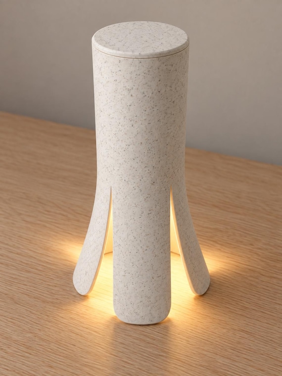 Elevated three-quarter view of the Lunareth lamp in White Marble, showing fine dark speckles, the circular top and curved lower openings.