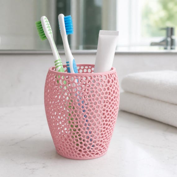 Sakura pink perforated toothbrush holder on a bathroom counter