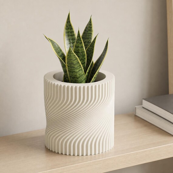 Bone White Swayline indoor planter with an upright snake plant on a home office shelf