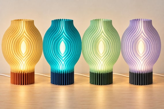 Four illuminated Veylora lamps on a wood tabletop, left to right: Sunlit Clay, Tidal Blue, Meadow Light and Orchid Dusk.