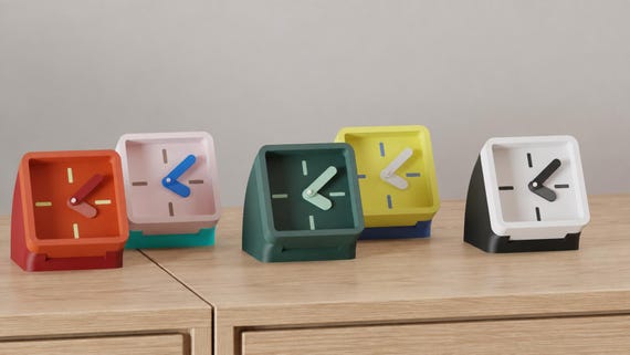 Alternate close-up of Framelean Desk Clock examples on light oak, showing their colored faces, hands and body profiles.