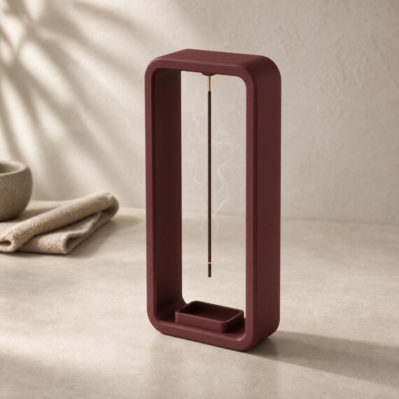 Close-up of a Maroon Red AeroCinder suspended incense stand in a calm meditation space