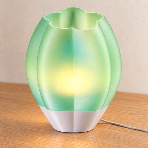 Elevated view of a Light Jade Veilcrest lamp with a white base, showing the scalloped shade opening, warm glow and gray power cord.