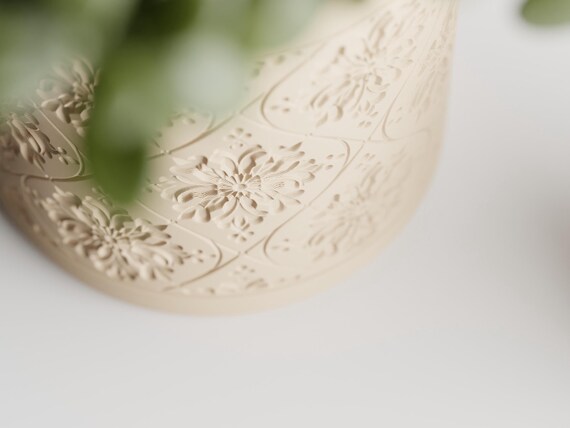 Angled detail view of the Petalweave planter's floral medallion relief
