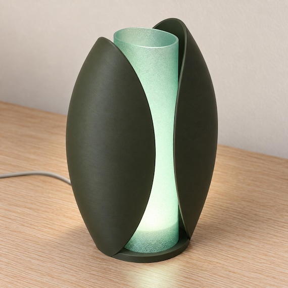 Elevated three-quarter view of the Forest Mist Lunafold lamp, with Dark Green curved outer panels, Light Jade open-top shade and gray power cord.