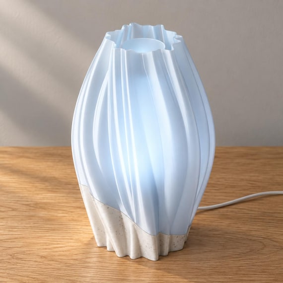 Elevated view of Marble Mist Orelune with a White Marble speckled base, Ice Blue outer shade and recessed cylindrical inner diffuser, with wired cord on oak.
