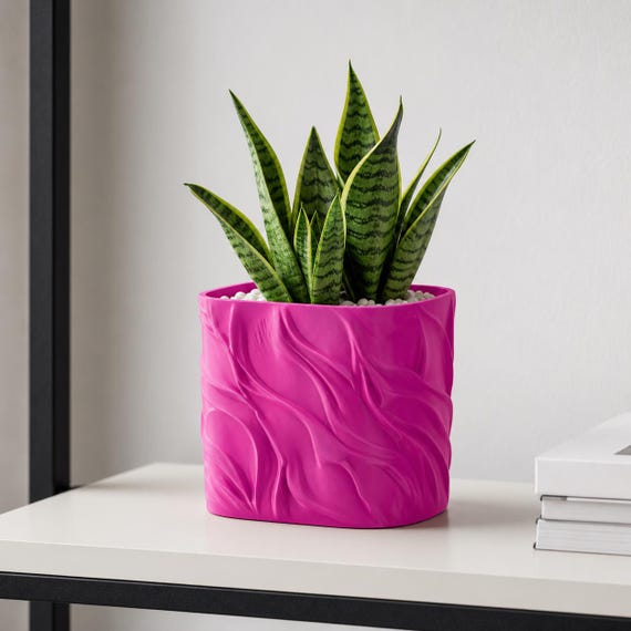 Magenta BreezeFold sculptural planter with an upright green snake plant on an office shelf