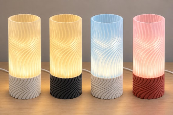 Four illuminated Seravelle lamps, left to right: Linen Glow, Midnight Glow, Marble Mist and Granite Rose, with spiral shades and matching ribbed bases.