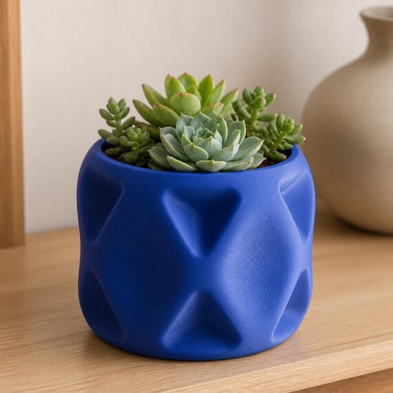 Close-up lifestyle view of a Cobalt Blue PillowFacet succulent planter on a light wood shelf