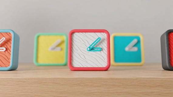 Angled close-up of Wildline Textured Desk Clock examples in contrasting colors on light oak against a gray wall.