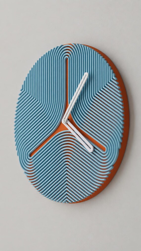 Triripple Wall Clock, blue curved ribs over a rust-colored round face with white hands, alternate source-referenced close-up on a gray wall.