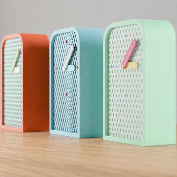 Latticehour Mesh Desk Clock examples in orange, blue and mint from an angled source view on oak, showing the perforated faces.